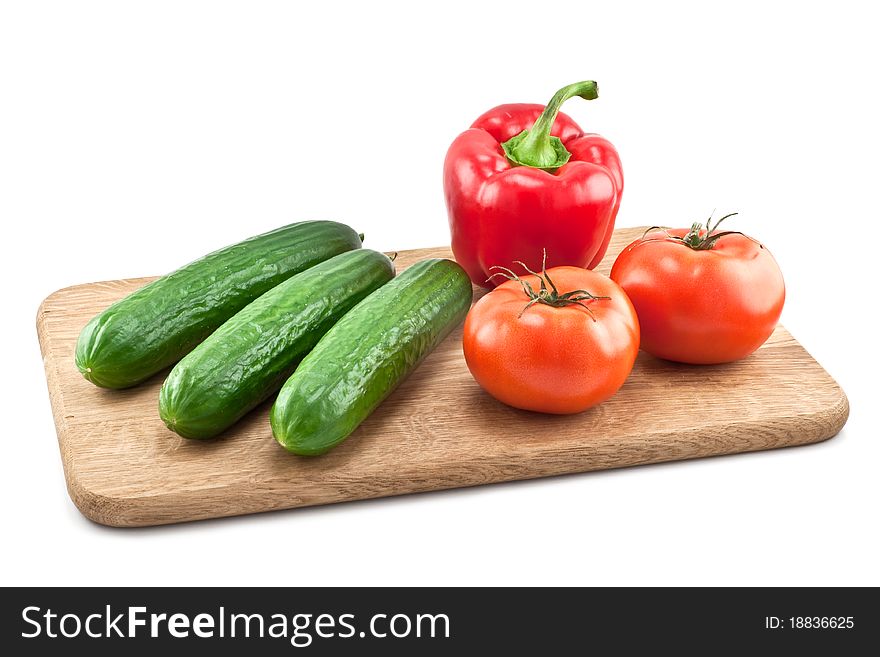 Cucumbers, tomatoes and peppers on wooden board isolated on white background