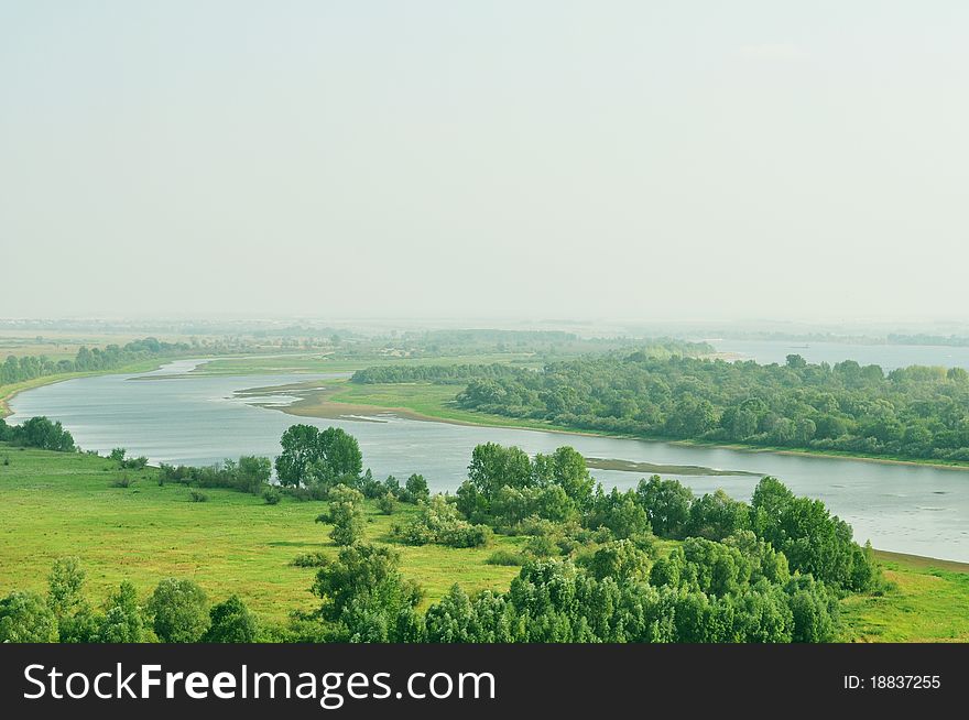 Channel, located between the field and forest, summer landscape, haze in the background, the photograph is a place for advertising slogan, mark or logo. Channel, located between the field and forest, summer landscape, haze in the background, the photograph is a place for advertising slogan, mark or logo