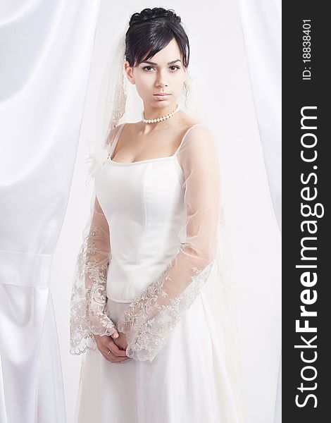 Beautiful bride stands on a white background