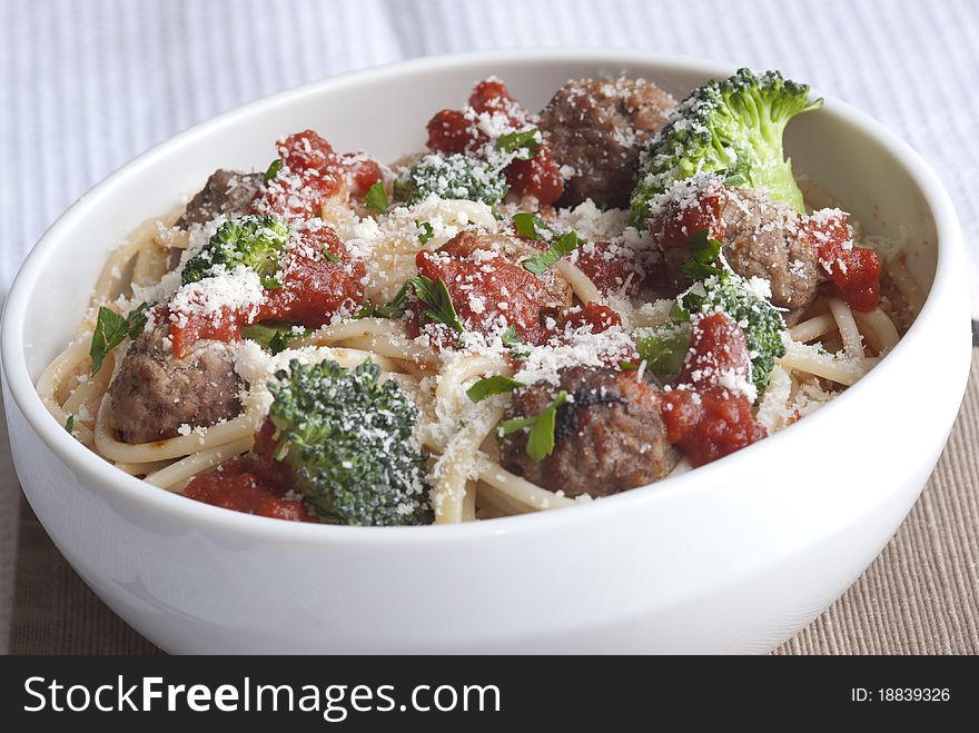 Beef meatballs with spaghetti and broccoli topped with grated parmesan. Beef meatballs with spaghetti and broccoli topped with grated parmesan