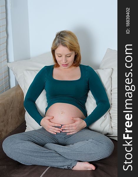 Young pregnant woman with hands on her abdomen.