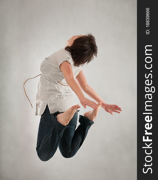 Girl jumping against grey wall