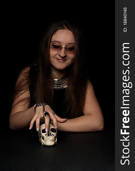Young beautiful witch with skull. Black background. Studio shot.