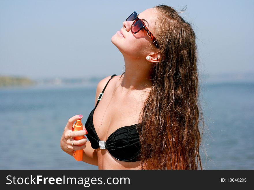 Pretty young caucasian woman spraying on the body against blue sky