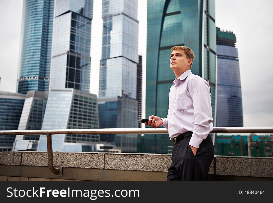 Thinking man with phone against backdrop of city