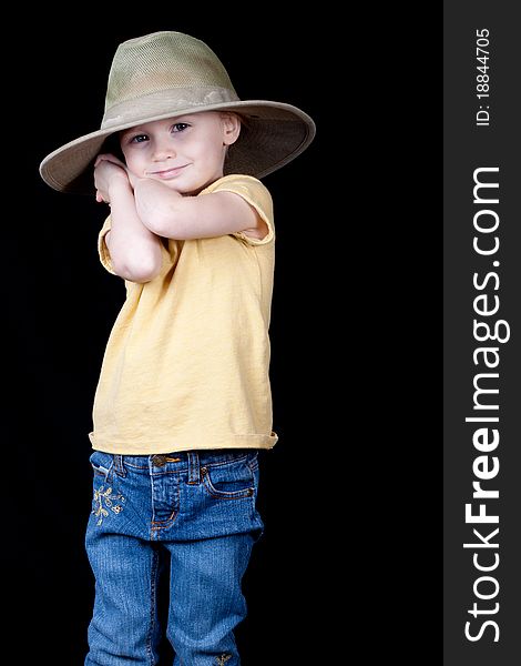 A girl with an oversized hat on. Her arms and hands are clasped behind her head as if she is holding something back or hiding something. A girl with an oversized hat on. Her arms and hands are clasped behind her head as if she is holding something back or hiding something.