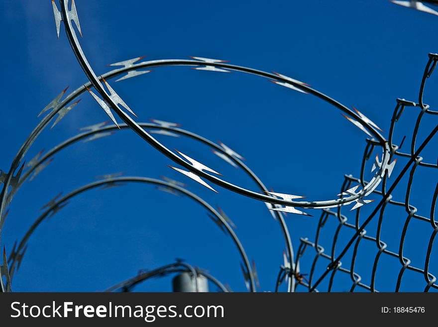Razor wire keeps criminals from climbing over the fence of the off-limits facility. Razor wire keeps criminals from climbing over the fence of the off-limits facility.