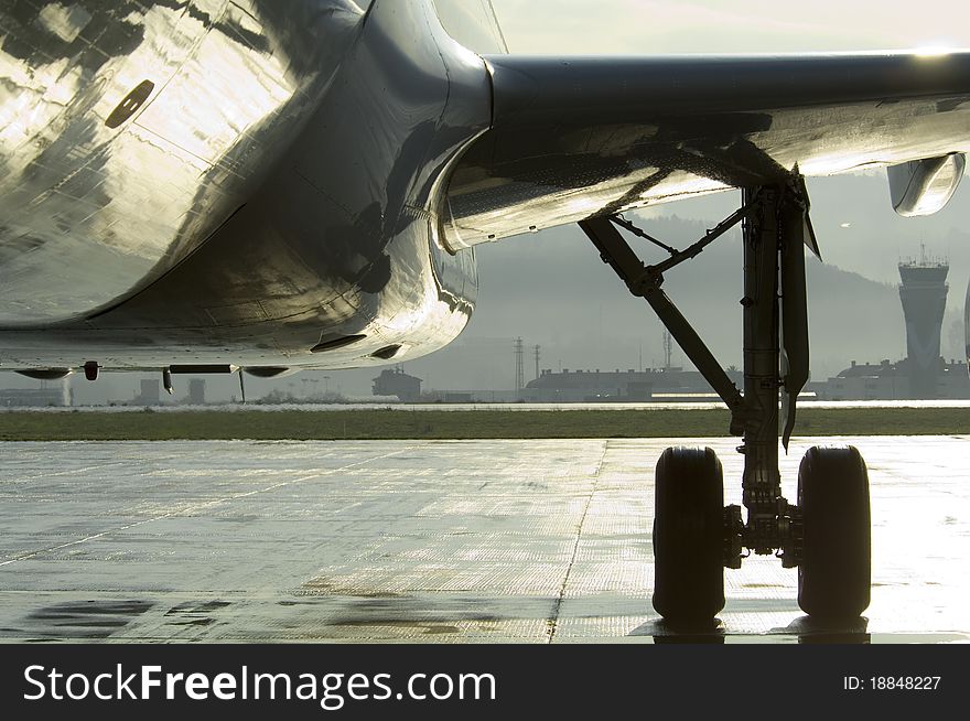 Aircraft landing gear detail with control tower in the background. Aircraft landing gear detail with control tower in the background