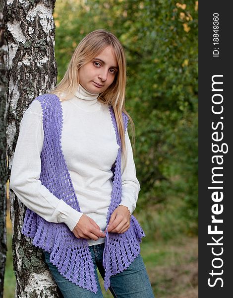 A girl in a lilac vest and white polo-neck sweater and jeans in a forest. A girl in a lilac vest and white polo-neck sweater and jeans in a forest