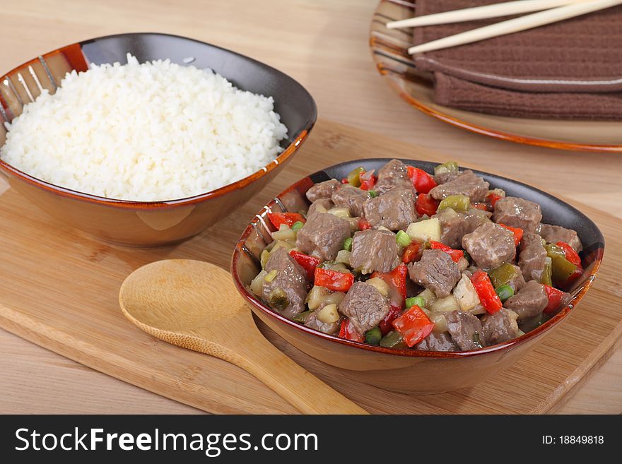Bowl of sweet and sour beef with peppers and a bowl of rice