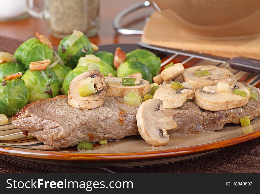 New York strip steak topped with mushrooms and brussels sprouts. New York strip steak topped with mushrooms and brussels sprouts