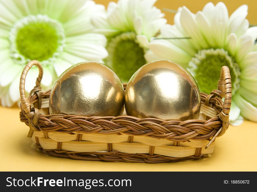 Two gold Easter eggs are in a wicker basket. Easter Traditions. Two gold Easter eggs are in a wicker basket. Easter Traditions