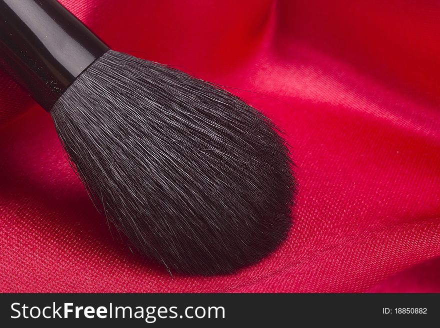 Powder brush with black hair on a red background.