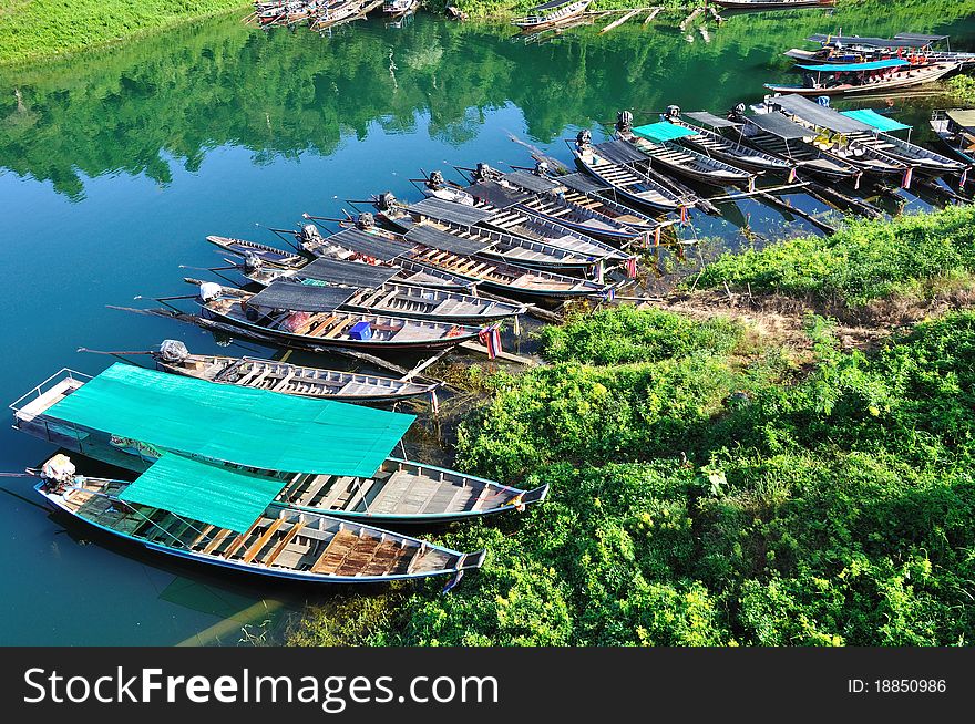Group of long tailed boats floating on green emeral lake.