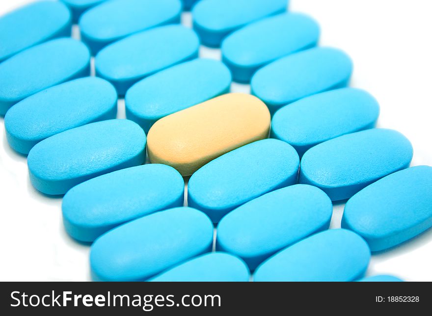 Some blue pills and one pink pill centered on a white background. Some blue pills and one pink pill centered on a white background