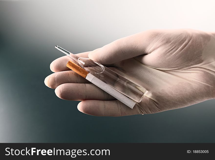 Hand in rubber glove with ampoule and cigarette. Hand in rubber glove with ampoule and cigarette.