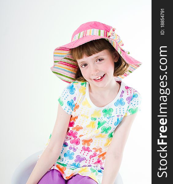 Little girl wearing colorful hat, sitting, leaning, isolated on white. Little girl wearing colorful hat, sitting, leaning, isolated on white.