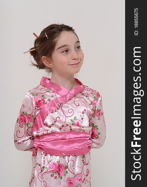 Cute smiling girl in Japanese masquerade costume standing with hands behind her back