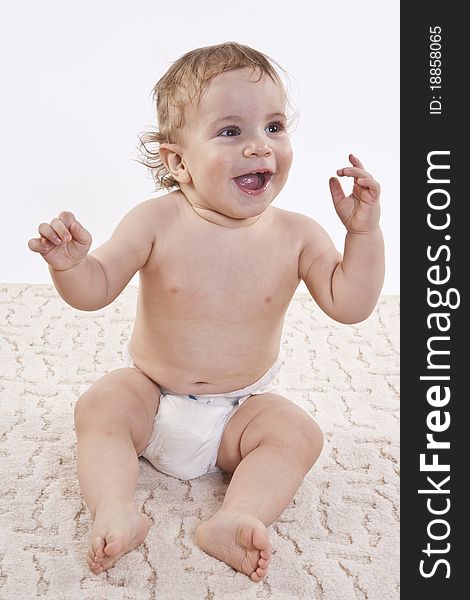 The charming boy sits on a carpet on a white background