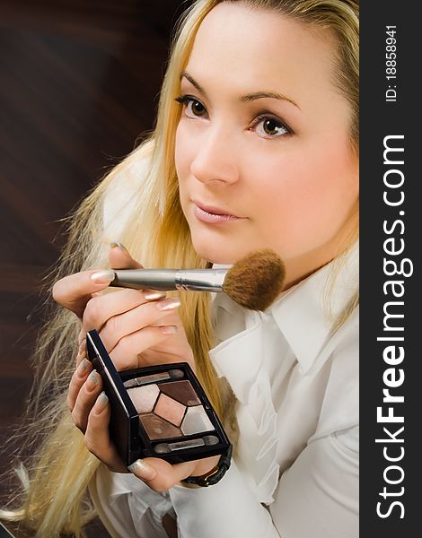 A blond girl with make-up brush and eye shadows. A blond girl with make-up brush and eye shadows
