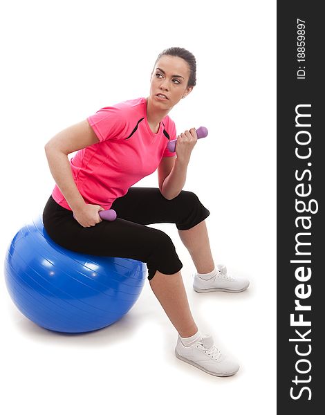 A young female lifting exercise weghts sat a blue exercise ball. A young female lifting exercise weghts sat a blue exercise ball