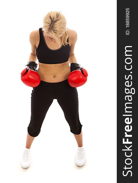 A female wearing red boxing gloves looking at the floor. A female wearing red boxing gloves looking at the floor