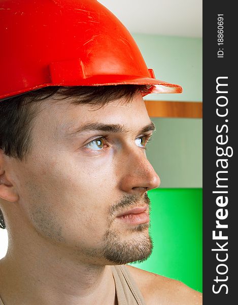 Young worker in a red building helmet on abstract background