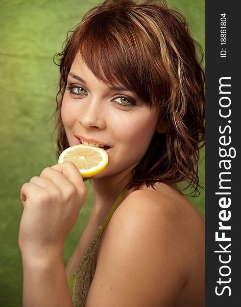 A beautiful young girl biting slice of lemon.