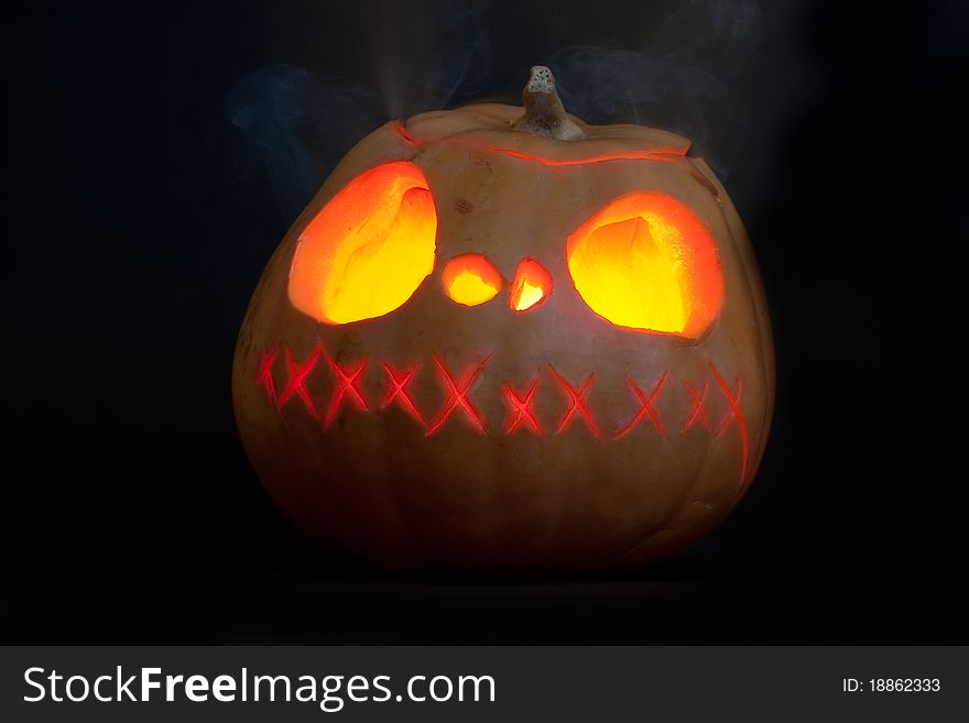 Halloween carved pumpkin, glowing and smoking in the dark. Halloween carved pumpkin, glowing and smoking in the dark