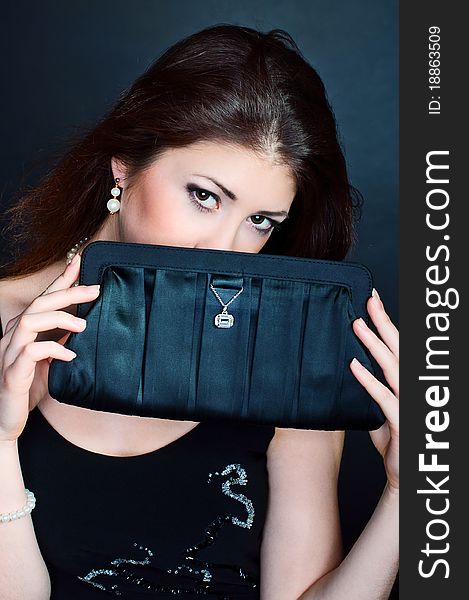 Young beautiful girl with purse on the black background. Young beautiful girl with purse on the black background