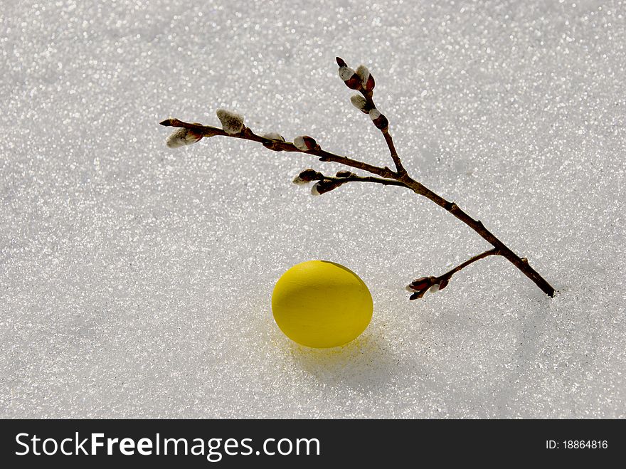 Yellow Easter egg on spring snow