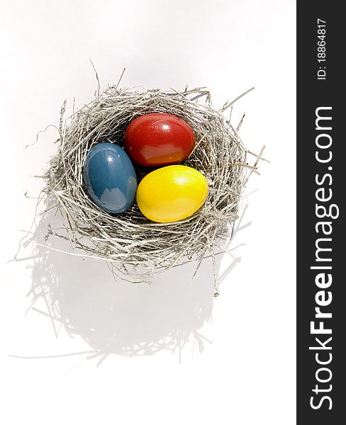 Nest with three color Easter eggs on white background. Nest with three color Easter eggs on white background