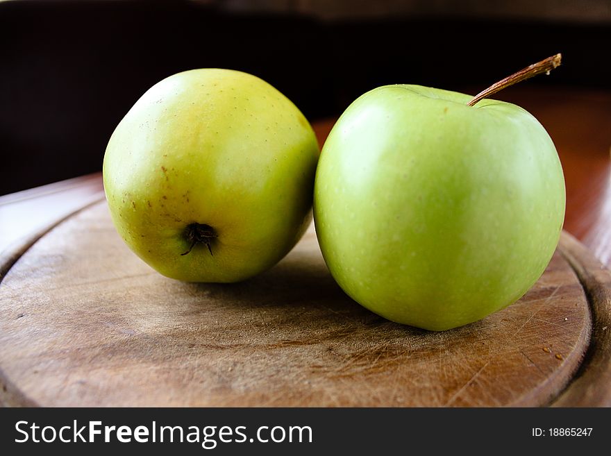 Two green apple on a wooden board
