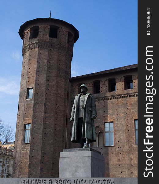 One of the towers of the Palazzo Madama in Turin, Italy, built during the 14th century. A statue of a soldier is standing in front of it.