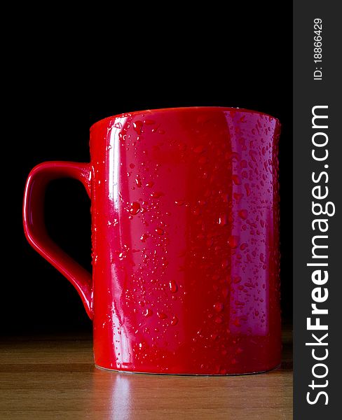 Red cup above table with black background