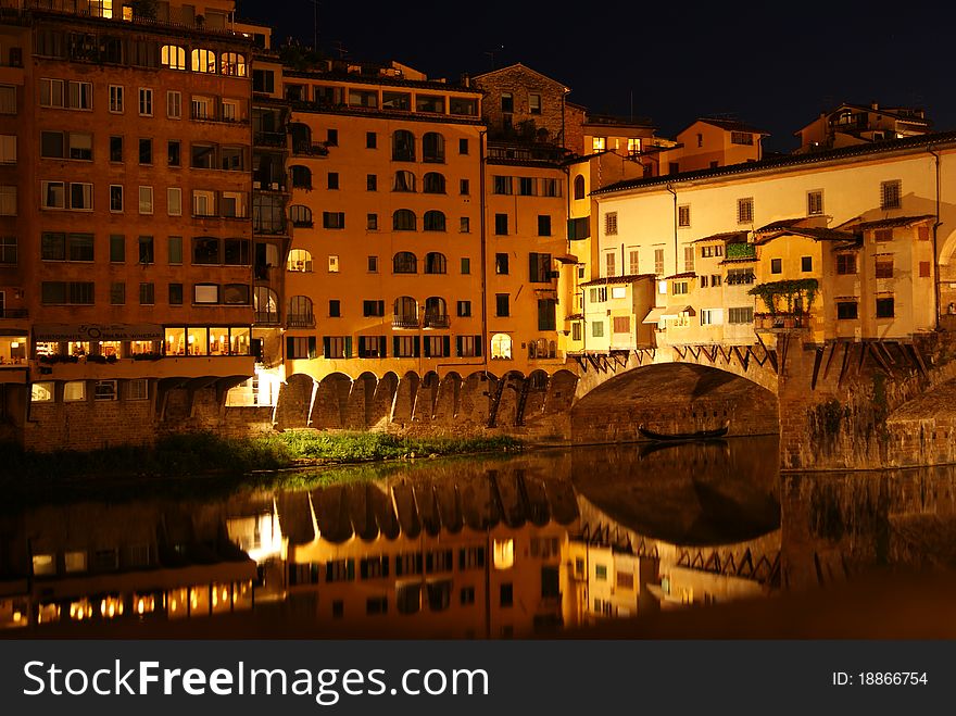 Reflections of the Ponte Vecchio in the River Arno by night in Florence, Italy