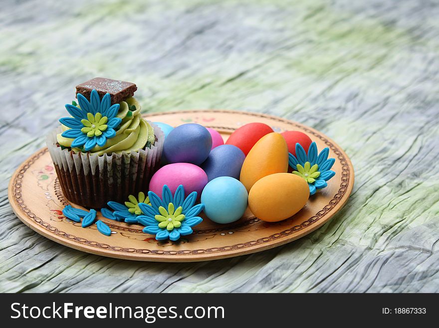 Chocolate cupcake with colorful easter eggs on an ornate plate. Chocolate cupcake with colorful easter eggs on an ornate plate