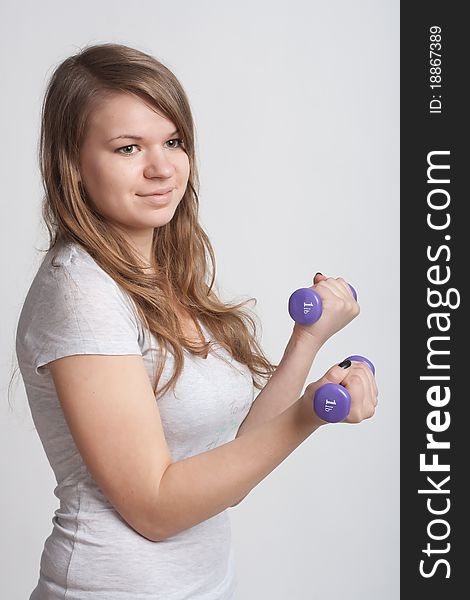 Girl on a white background with dumbbells in hand. Girl on a white background with dumbbells in hand