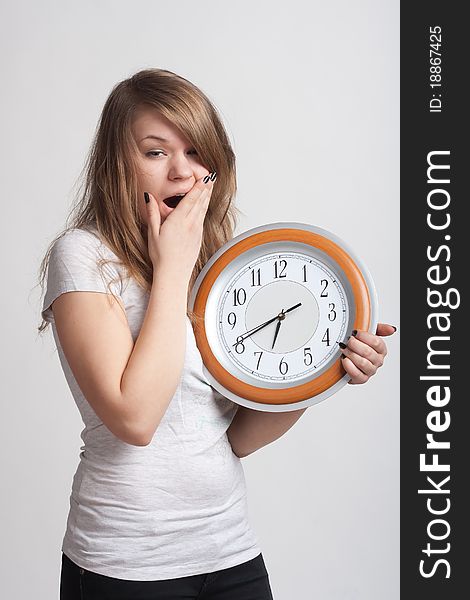 Sleeping girl on a white background with a big clock in the hands of which 6.40 am. Sleeping girl on a white background with a big clock in the hands of which 6.40 am