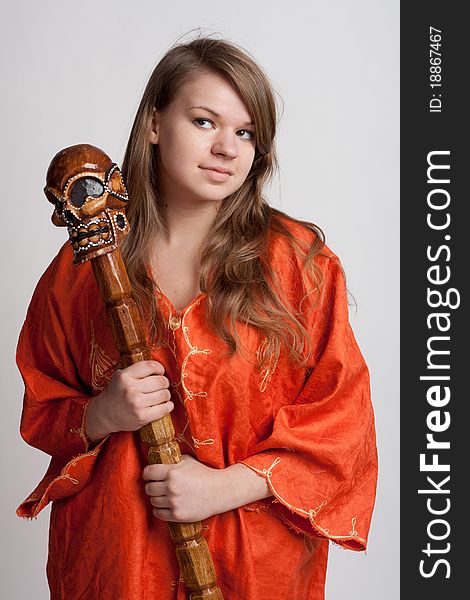 Girl in orange dress on a light background with a staff. Girl in orange dress on a light background with a staff
