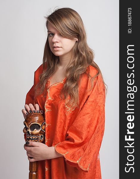 Girl in orange dress on a light background with a staff. Girl in orange dress on a light background with a staff