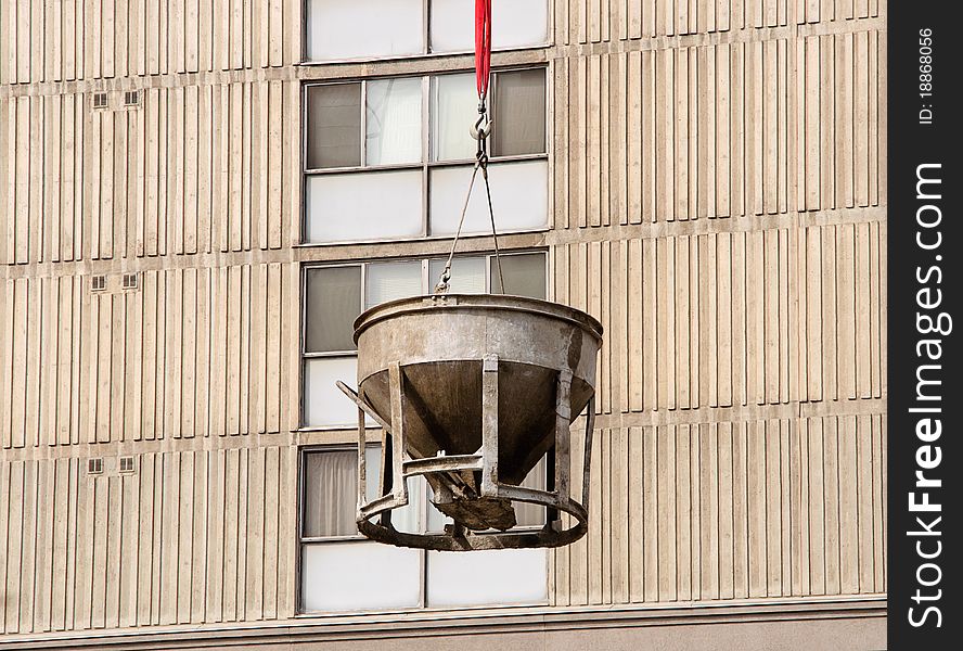 Cement bucket swinging against building