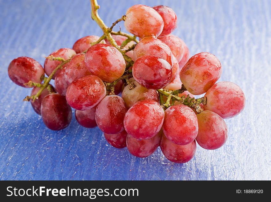 Photo of delicious red grape on blue glass table. Photo of delicious red grape on blue glass table