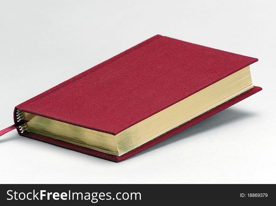 Red plain book with gold coloured pages on a light background. Red plain book with gold coloured pages on a light background