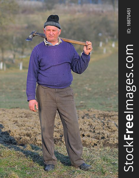 Posing woodcutter near the forest with a hatchet on his shoulder.