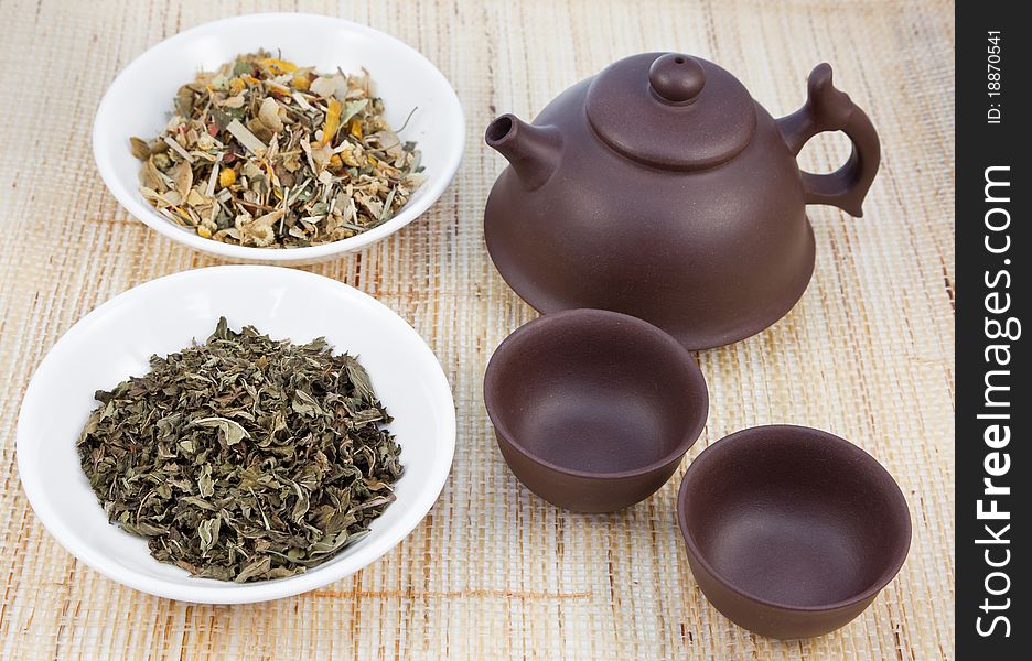 Chinese tea set with herbal teas on natural matting. Chinese tea set with herbal teas on natural matting.
