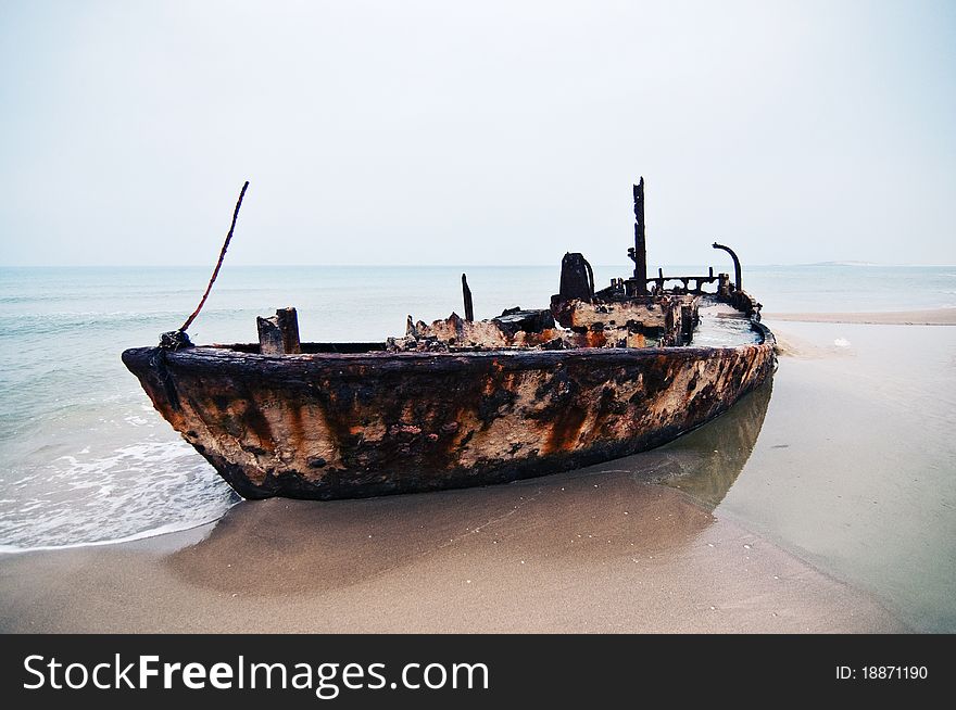 An old rusty ship thrown on a deserted beach. An old rusty ship thrown on a deserted beach