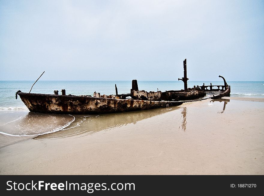 An old rusty ship thrown on a deserted beach. An old rusty ship thrown on a deserted beach