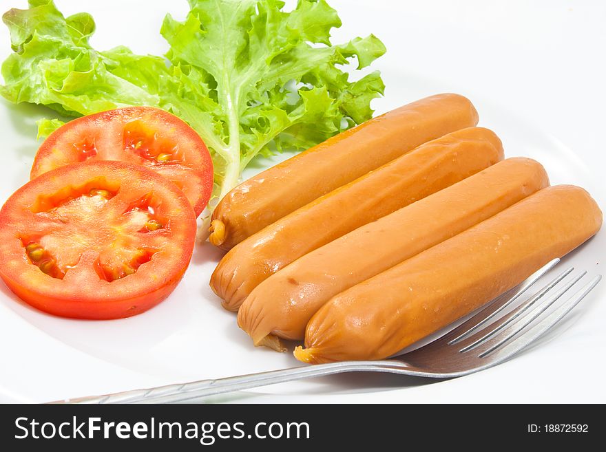 Sausages with fork in the white dish