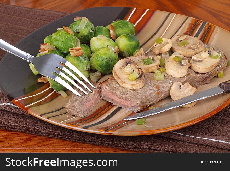 New York strip steak topped with mushrooms and brussels sprouts. New York strip steak topped with mushrooms and brussels sprouts